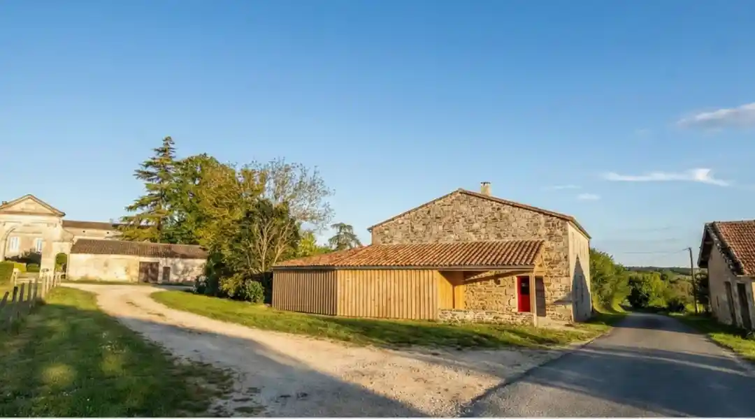 Construction d'un garage à Saint-émilion Paysage rural avec des bâtiments de ferme et un chemin sous un ciel clair.